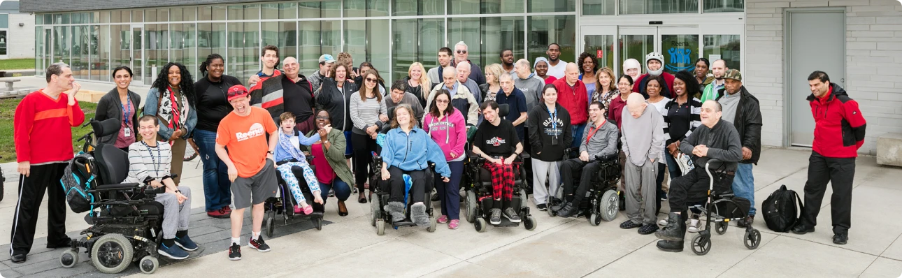 Students supported by Reena nonprofit standing outside a community building, reflecting inclusive programs for individuals with developmental disabilities