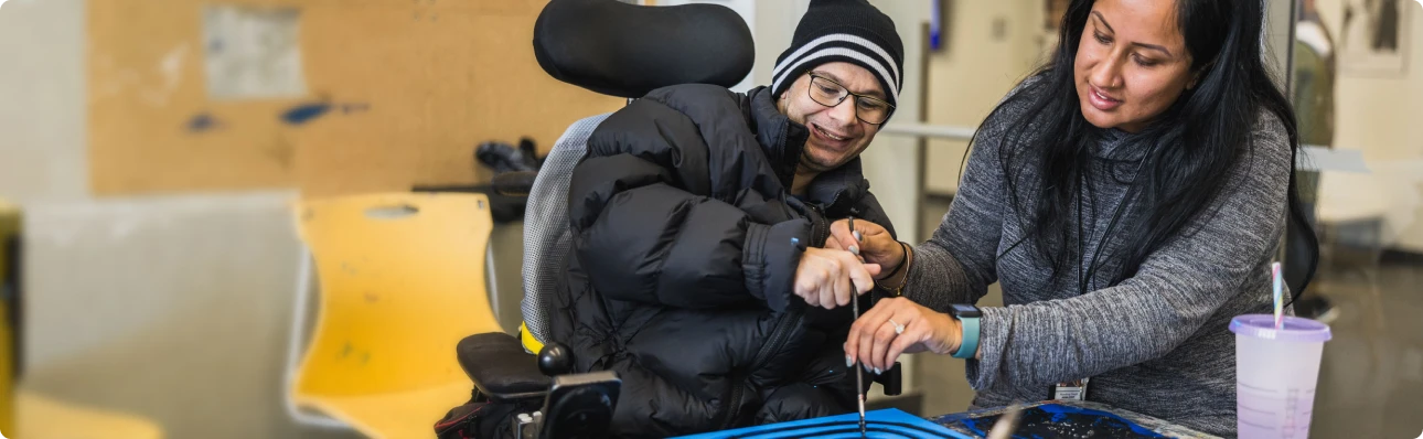 Reena nonprofit staff member supporting a student with developmental disabilities during a hands-on activity.